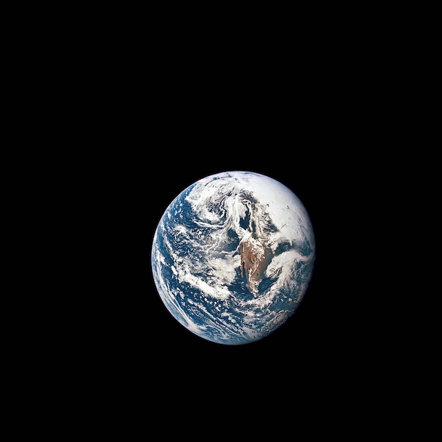 Earth against a black background. White cloud systems swirl over blue oceans and brown-green landmasses.
