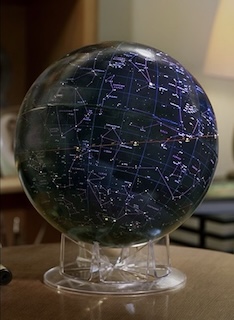 A globe-style model of the celestial sphere sitting on a desk.