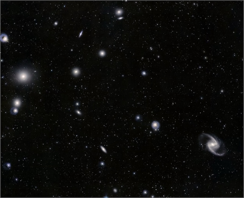 About twenty small galaxies are scattered across the image, with fuzzy circular, elliptical, and spiral shapes.