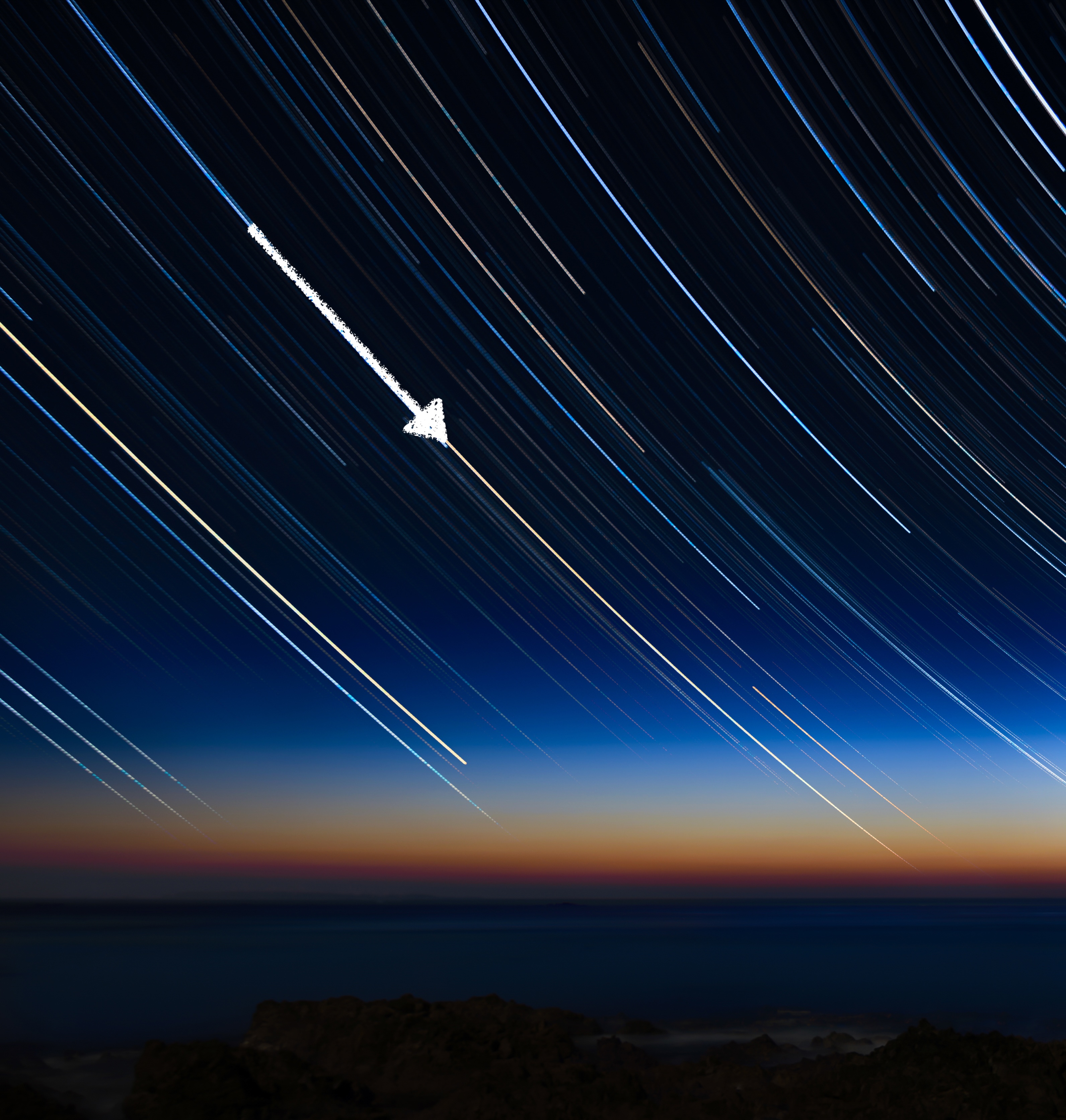 Star trails go from upper left to lower right in the image. An arrow points downward and to the right along a trail.