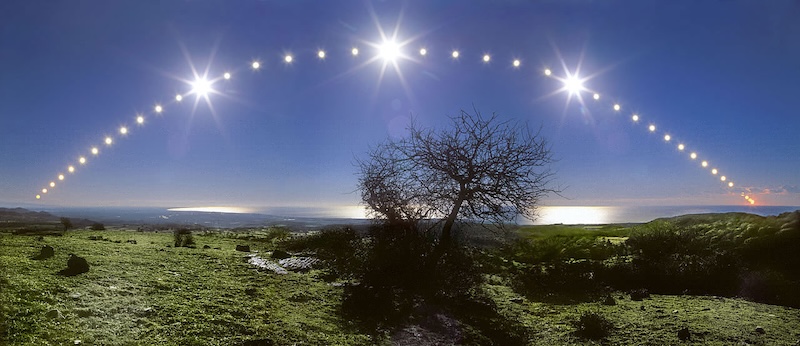 43 images of the sun arc across the blue sky over a sea view from a grassy field with a tree